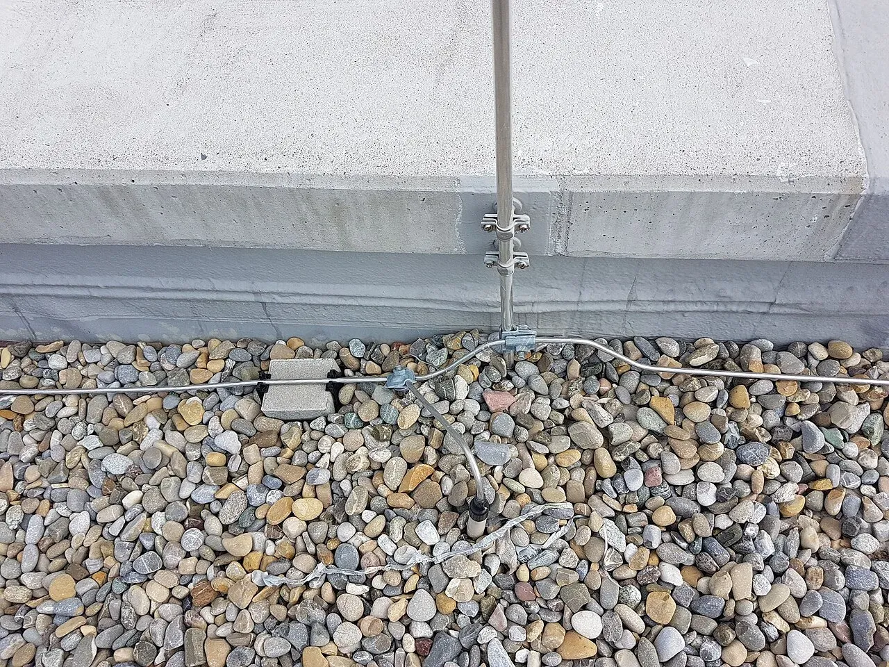 Air terminal on a parapet connected to a roof conductor on a gravel-ballasted flat roof, part of a commercial lightning protection design