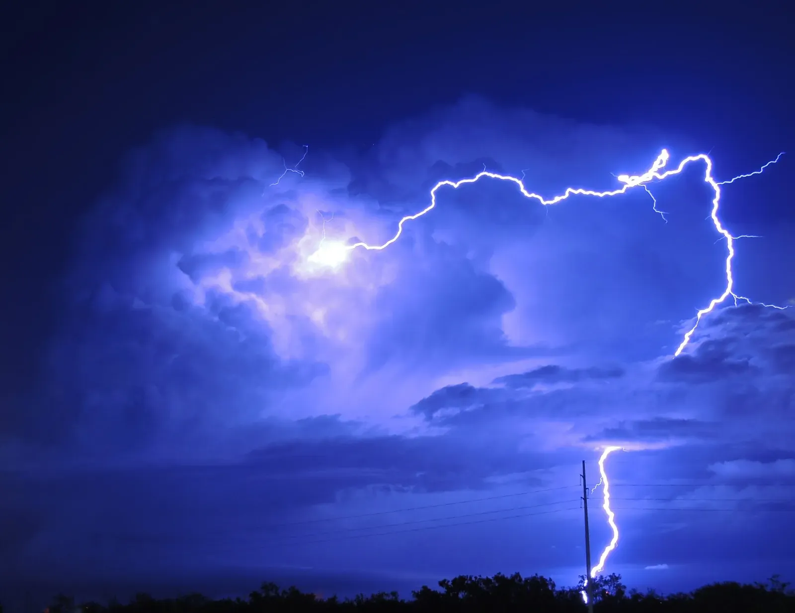 Cloud-to-ground lightning striking beside a power pole at night in Texas