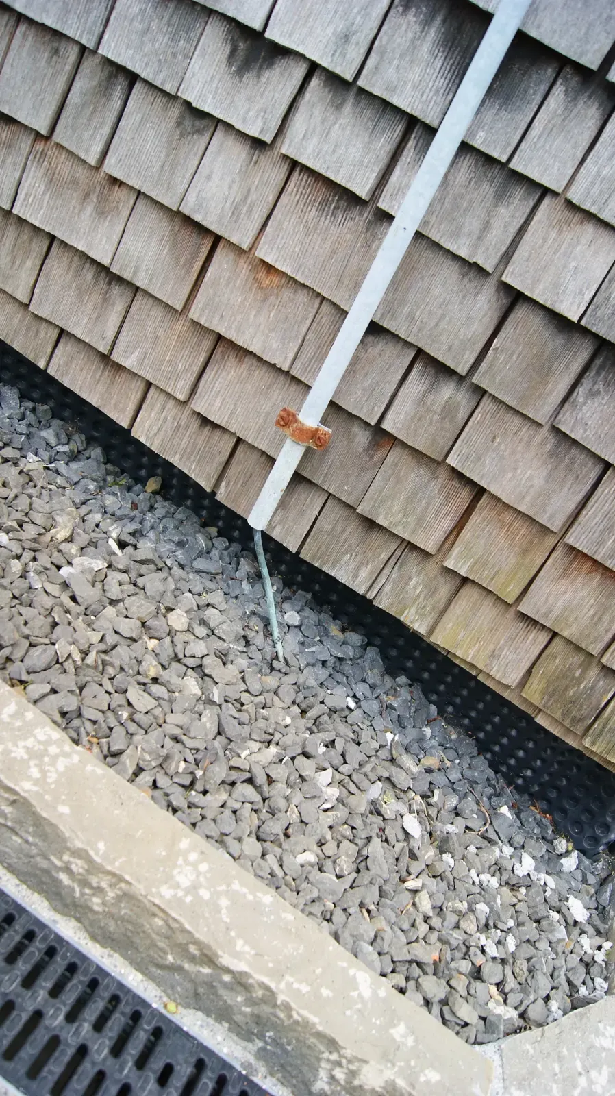 Copper lightning protection conductor fastened along the edge of a wood-shingle roof