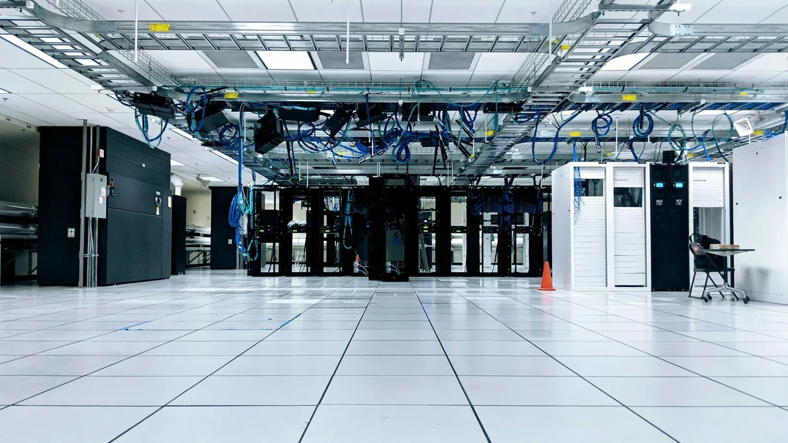 Data center server room with rows of network cabinets under overhead cable trays