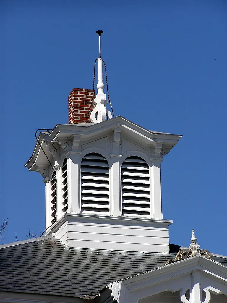 Lightning rod on top of a white cupola on a house roof