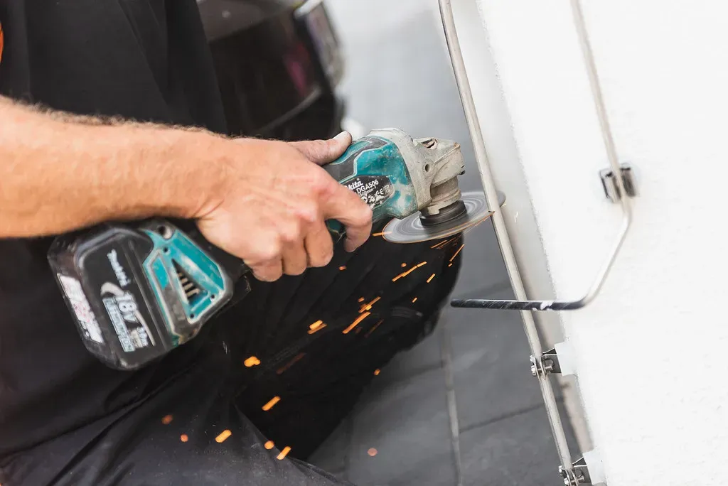 Installer cutting a lightning protection conductor rod with an angle grinder