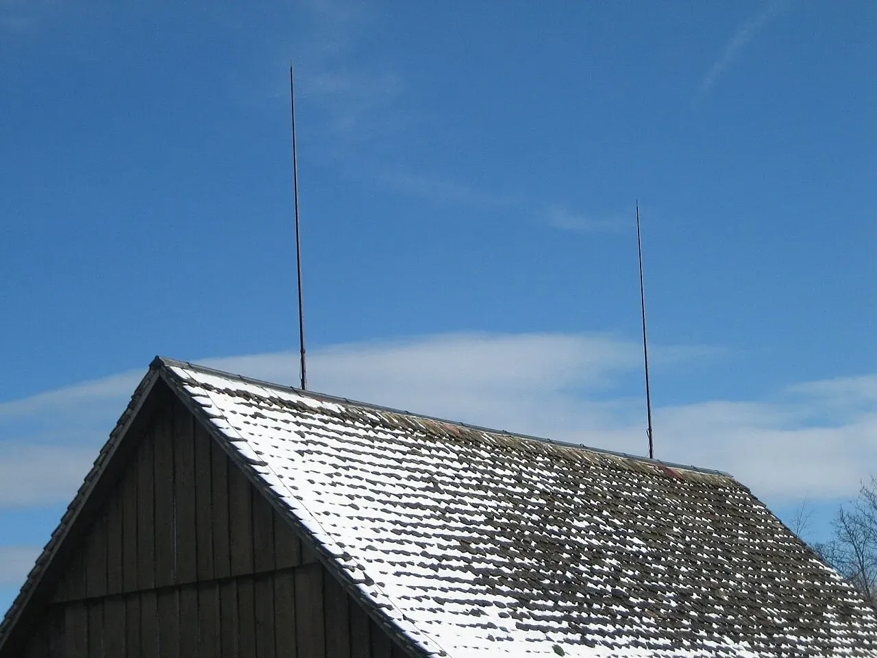 Two tall lightning rods on the ridge of an old barn roof
