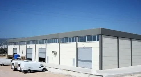 White commercial building with roll-up doors and vans parked outside