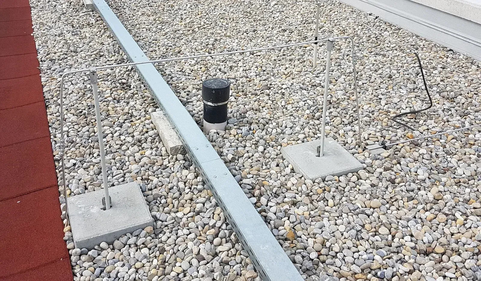Lightning protection conductor on supports bridging over a cable duct on a gravel flat roof